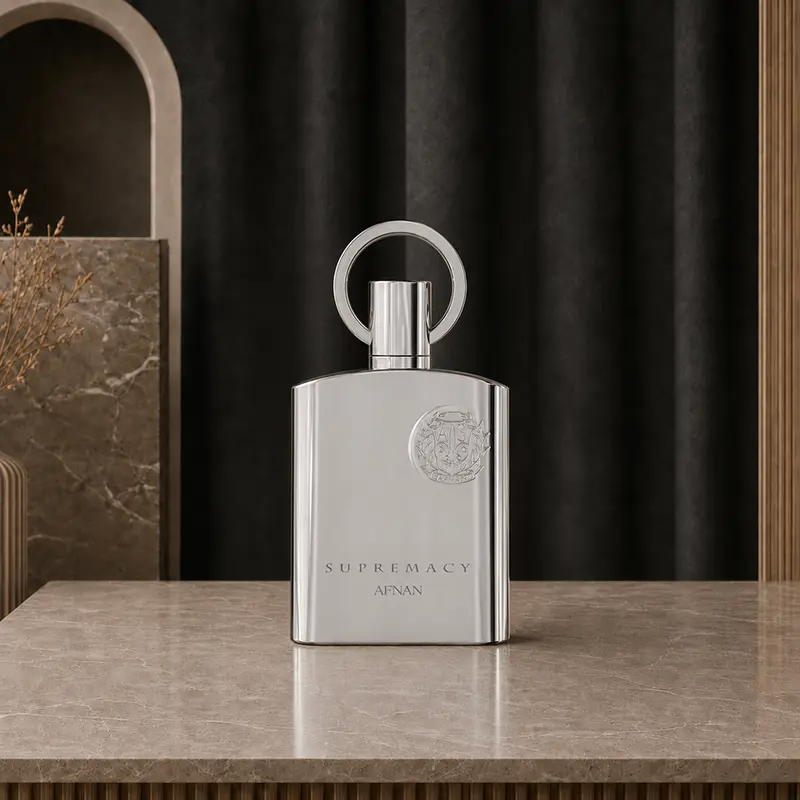 Afnan Supremacy Silver chrome bottle stands front-facing against a black curtain in a marble studio