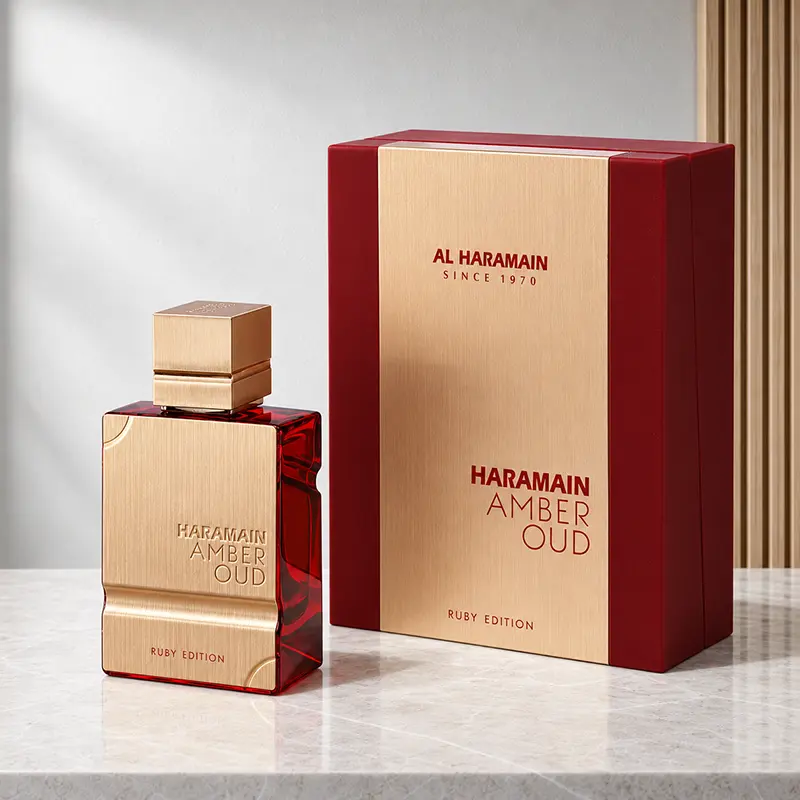 Amber Oud Ruby Edition bottle beside its matching red-and-gold box in an angled studio view.