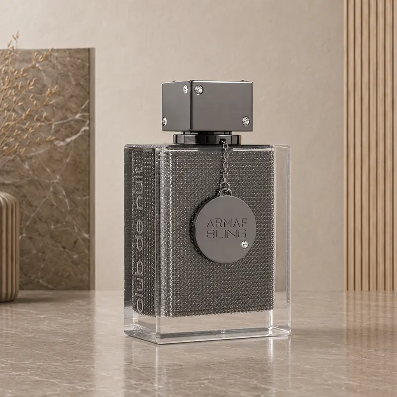 Angled studio view of the Club de Nuit Bling bottle, showing clear glass, a textured panel and metal charm
