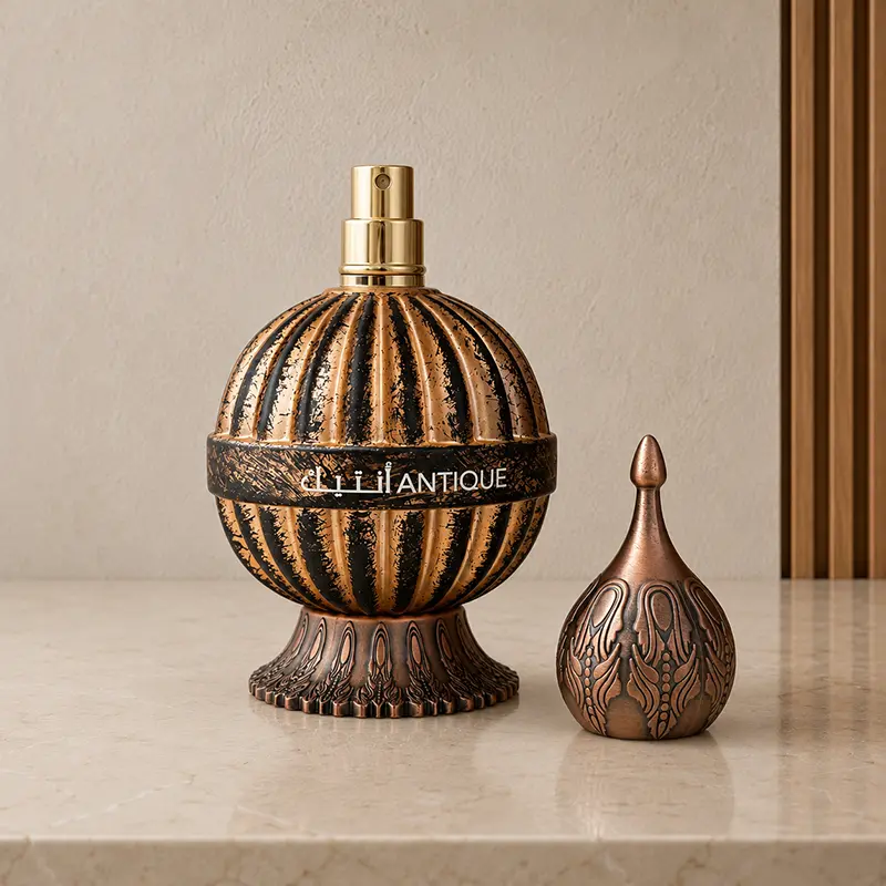Antique bottle with cap removed, showing the gold atomizer and ornate bronze-toned cap beside it.