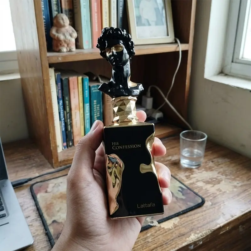 A person holding the 100 ml spray bottle, displaying its geometric lines and solid grip profile.
