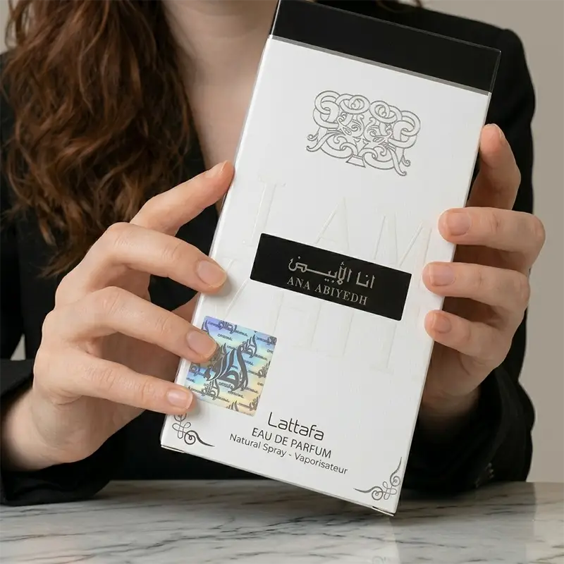 Detail shot of the holographic authenticity seal on the Lattafa Ana Abiyedh packaging held by a hand.