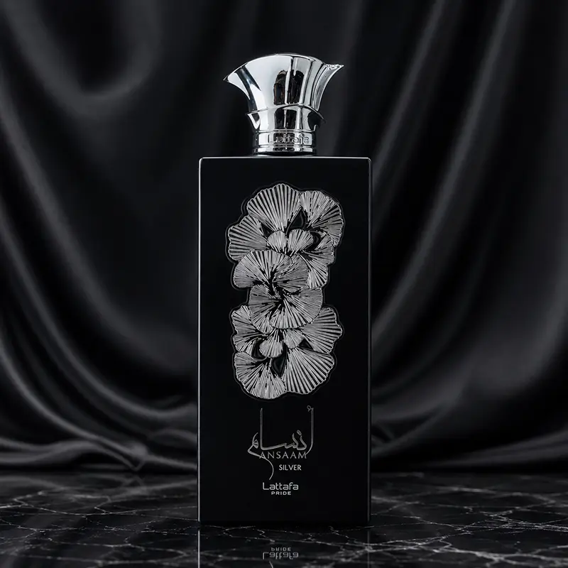 The sleek matte black vertical bottle of Ansaam Silver featuring an intricate raised silver leaf decoration.