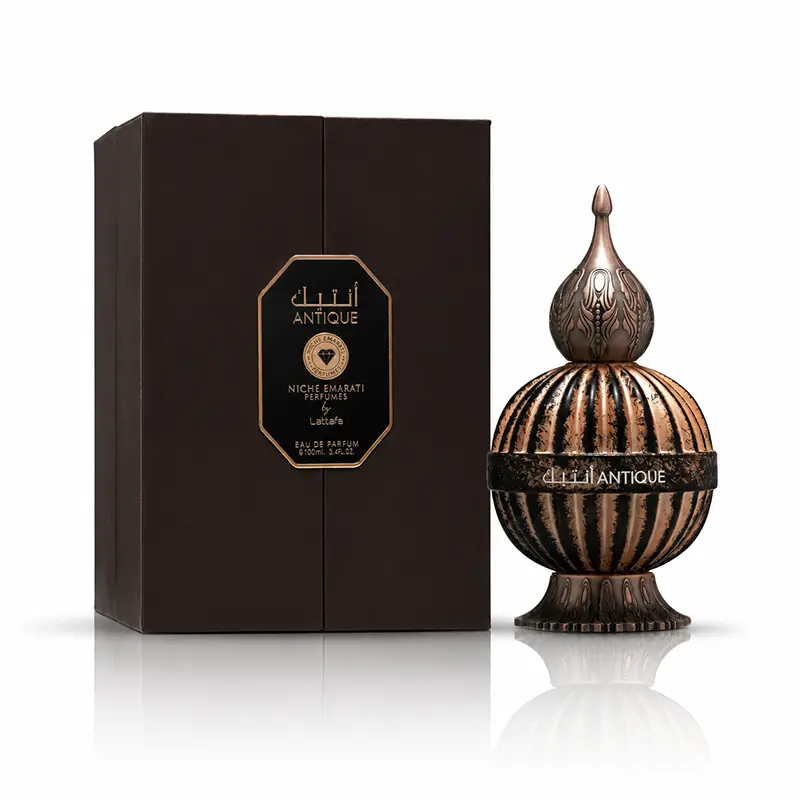 Lattafa Antique 100ml bottle beside its dark presentation box on a white background with reflection.