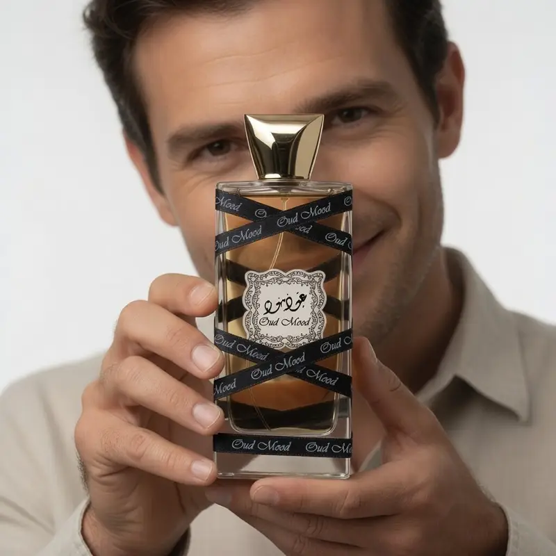 Smiling man holding Lattafa Oud Mood perfume, highlighting the saffron and oud wood fragrance for men and women.