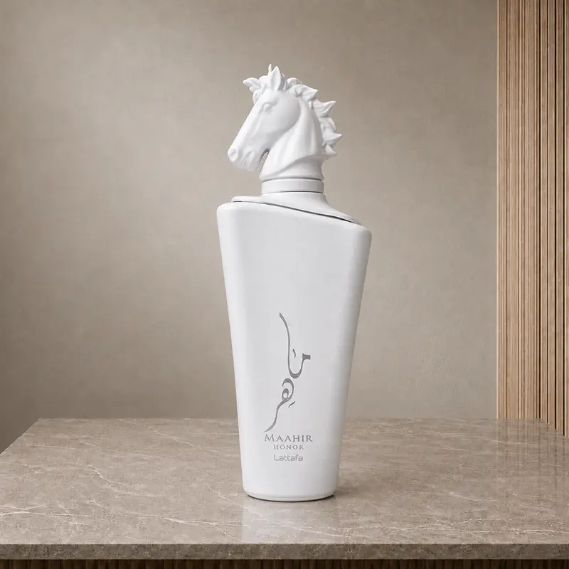 White Maahir Honor perfume bottle with sculpted horse-head cap on a stone surface.
