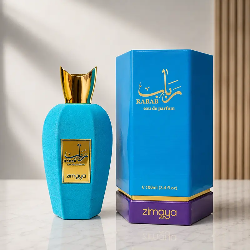 Rabab Blue bottle beside matching blue box with gold and purple packaging in the studio.