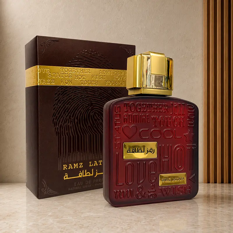 Ramz Lattafa Gold bottle and box in an angled studio view with burgundy and gold packaging details.