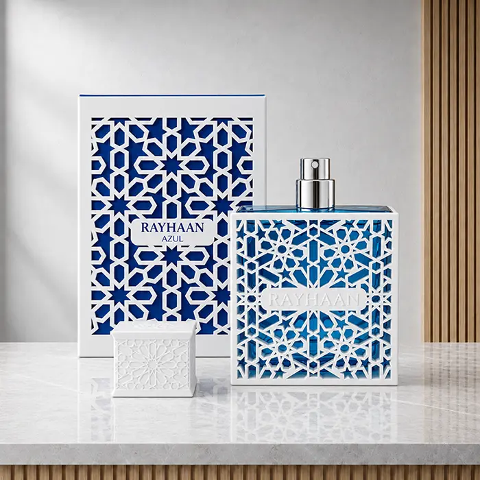 Uncapped Azul perfume bottle with exposed spray nozzle, patterned box and detached white cap on a marble surface.