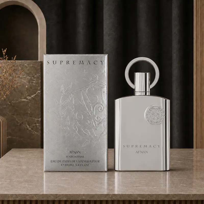 Embossed Supremacy Silver box and chrome bottle stand side by side on a marble counter with a black backdrop