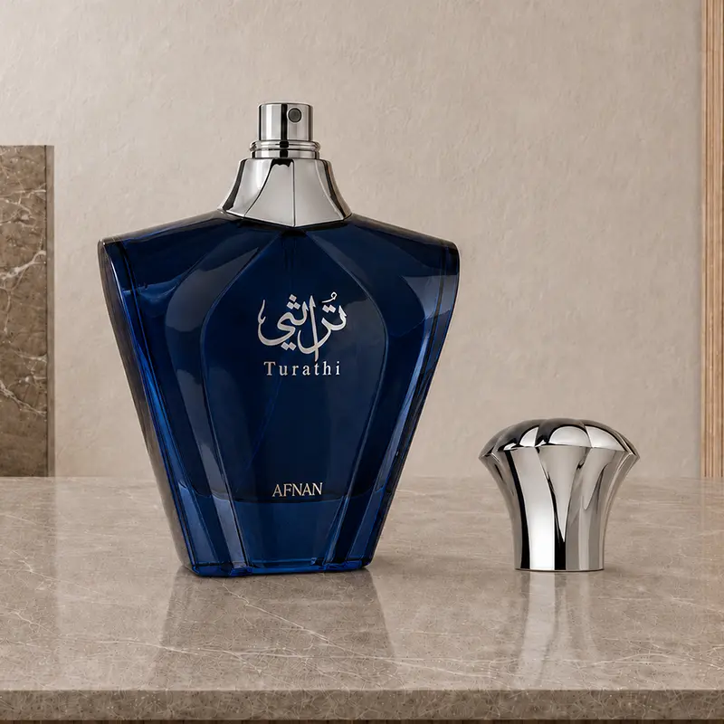 Turathi Blue bottle with exposed spray nozzle and detached silver cap on a marble studio surface.